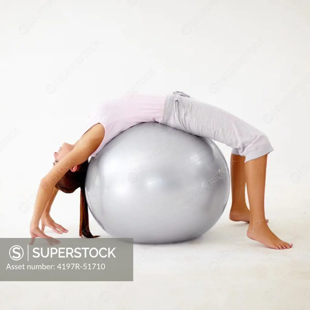 Young woman bending backwards over a physio ball