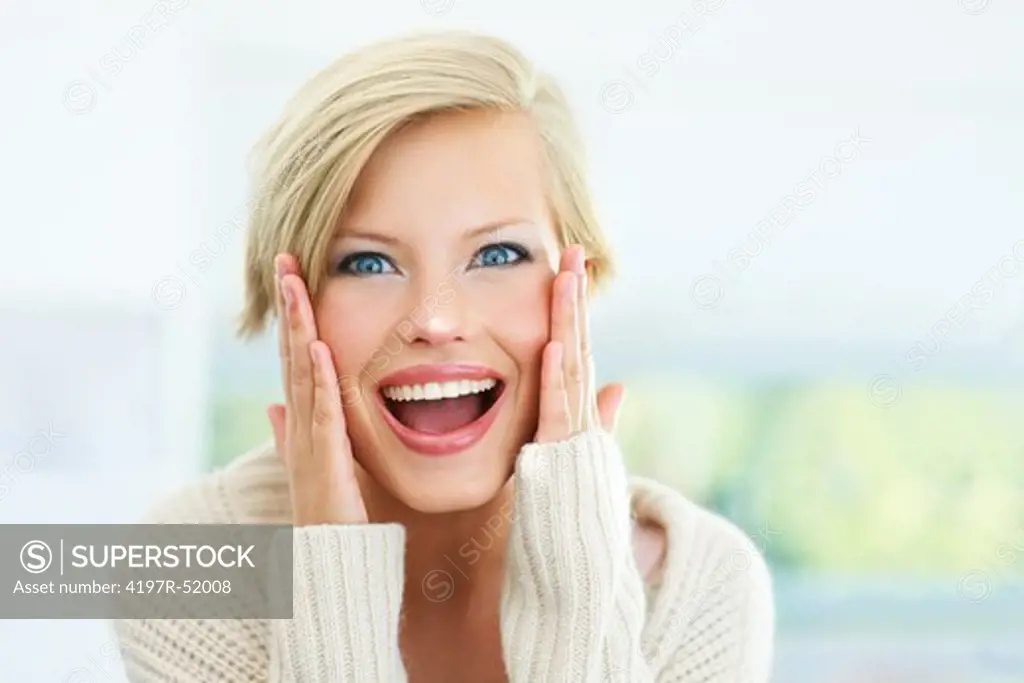 Excited young woman with her hands on her cheeks looking at you