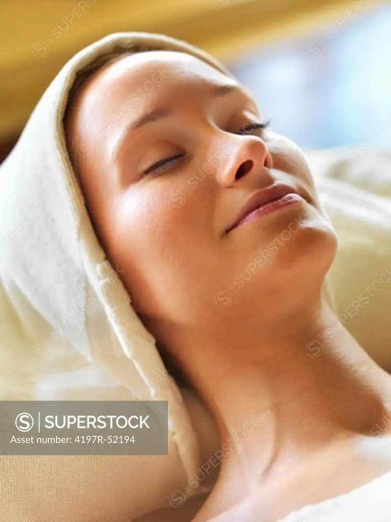 Closeup of attractive middle aged woman smiling while relaxing on spa table