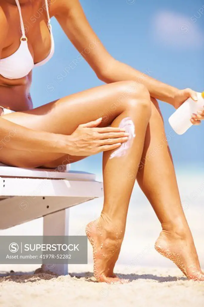 Woman applying sunscreen lotion on legs