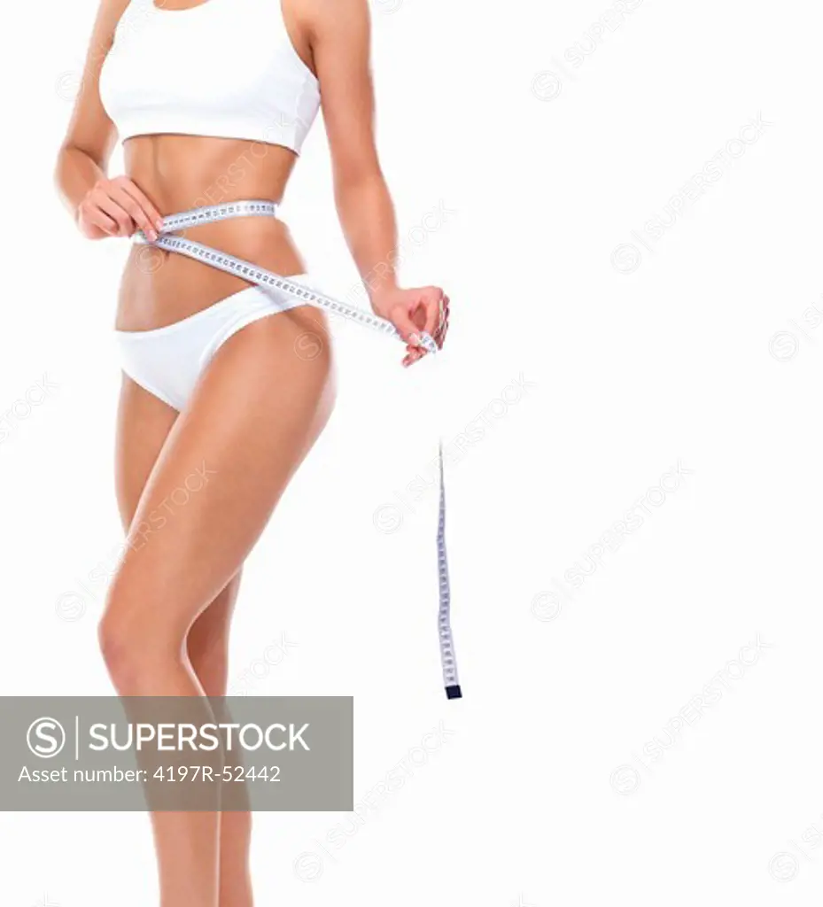 Portrait of young conscious woman measuring her waist over white background