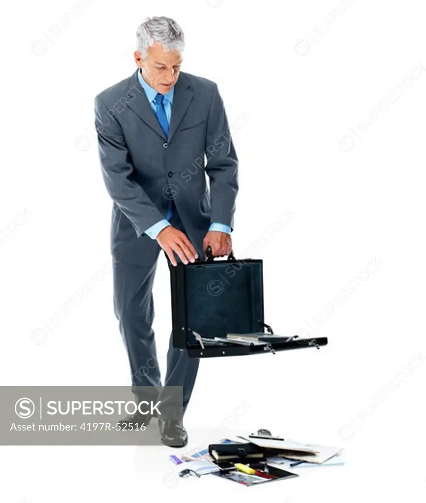 Senior businessman looking at papers falling out of his suitcase on white background