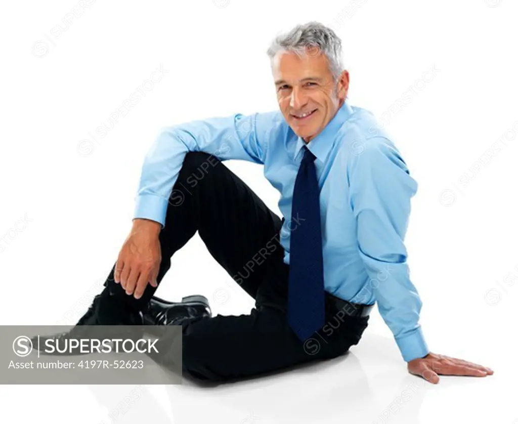 Relaxed mature business man sitting on the floor isolated over white background