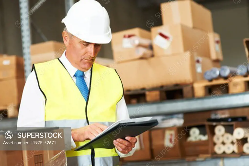 Mature warehouse worker checking his stock on a clipboard