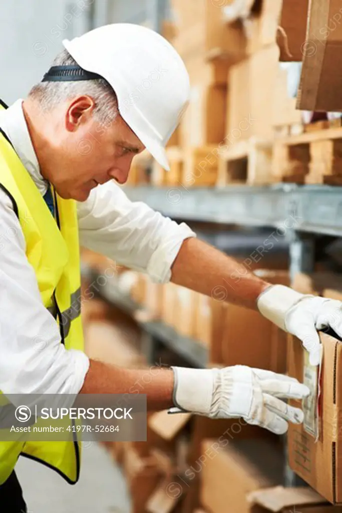Mature male supervisor inspects the barcodes on a box of his stock wearing white gloves