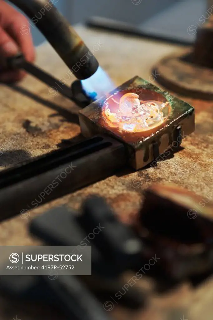 Closeup of a goldsmith melting gold with a blowtorch