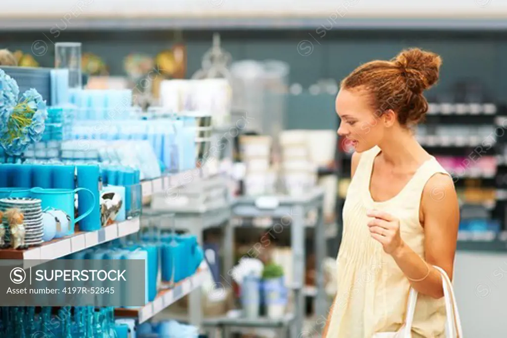 Attractive woman standing in aisle looking at blue merchandise on shelves