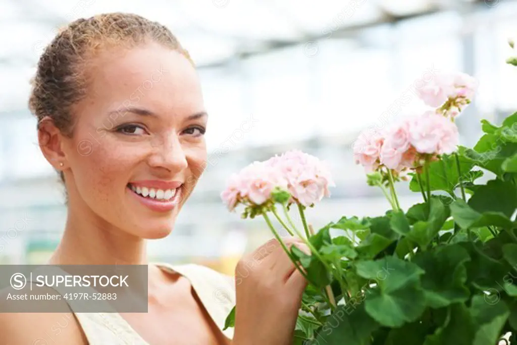 Closeup of young ethnic woman holding bunch of flowers looking and smiling at camera