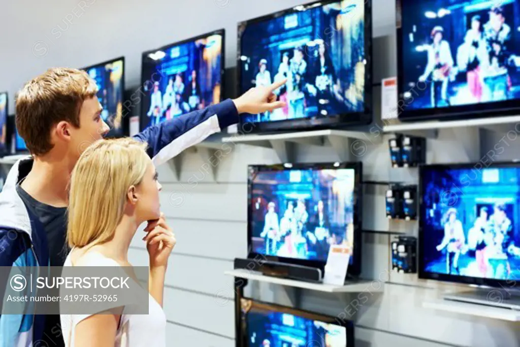 Young man showing new televison in store shelf to his girlfriend