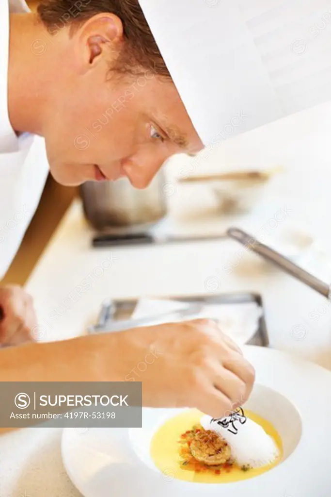 Young cook doing finishing touch to dessert in kitchen