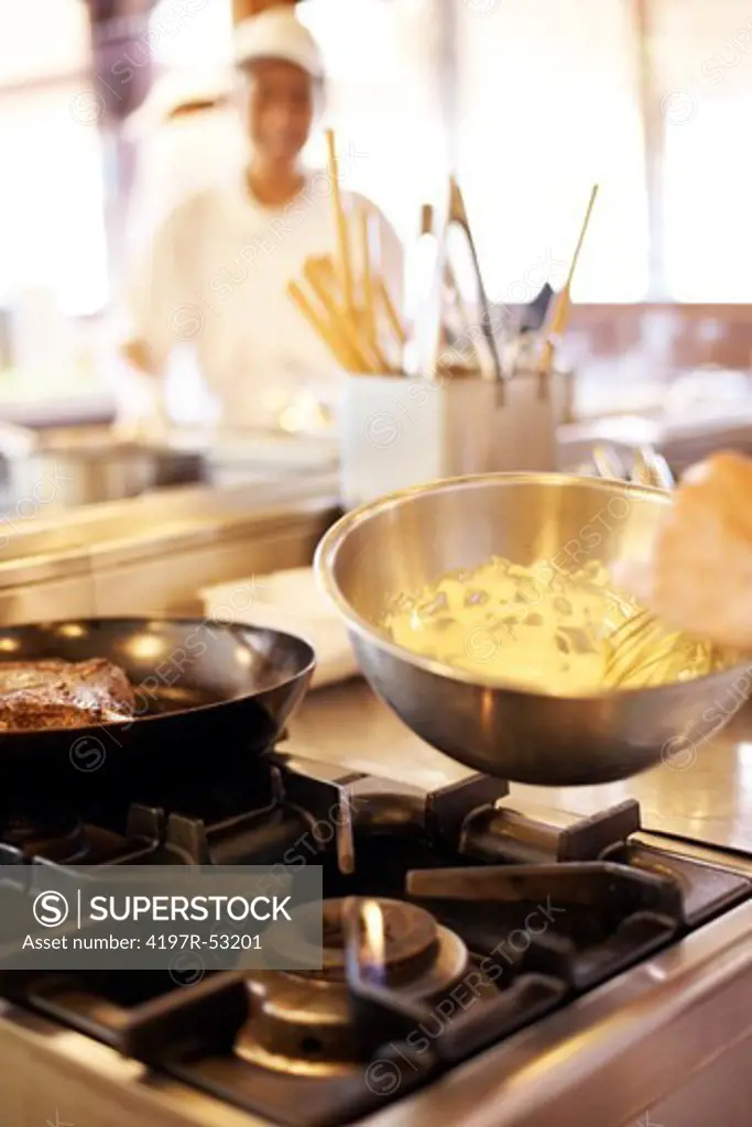 Closeup of chef cooking a dish on stove in restaurant kitchen