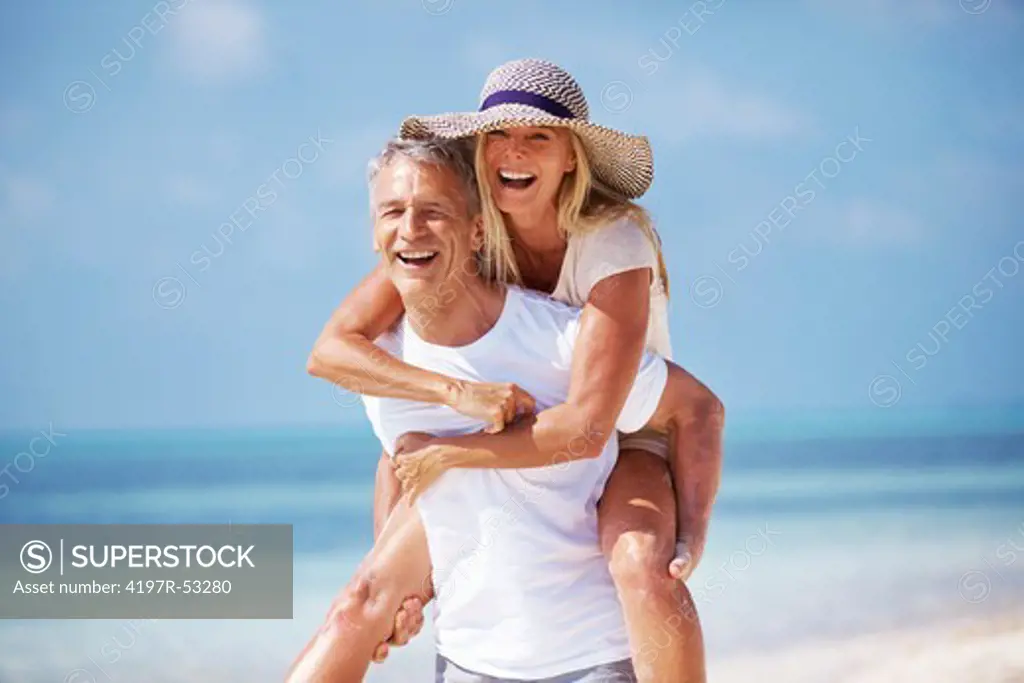 Portrait of mature man giving piggyback ride to woman on beach