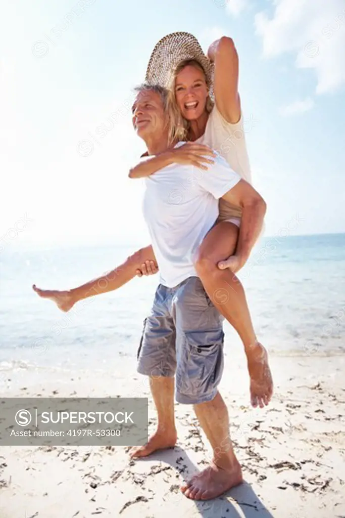 Full length of mature couple having fun while piggybacking on beach