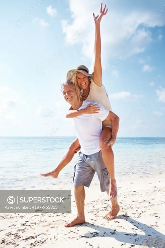 Full length of mature man giving piggyback ride to woman on beach