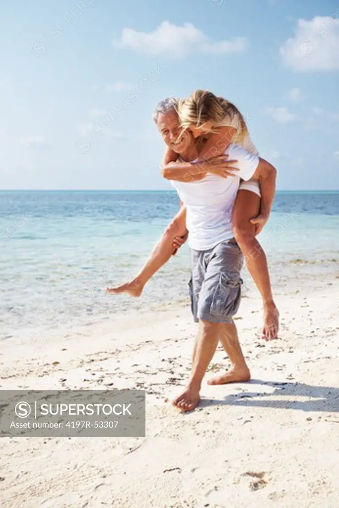 Full length of loving couple having fun while piggybacking on beach