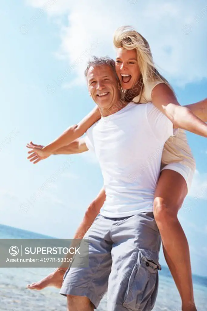 Portrait of happy mature man carrying woman on beach