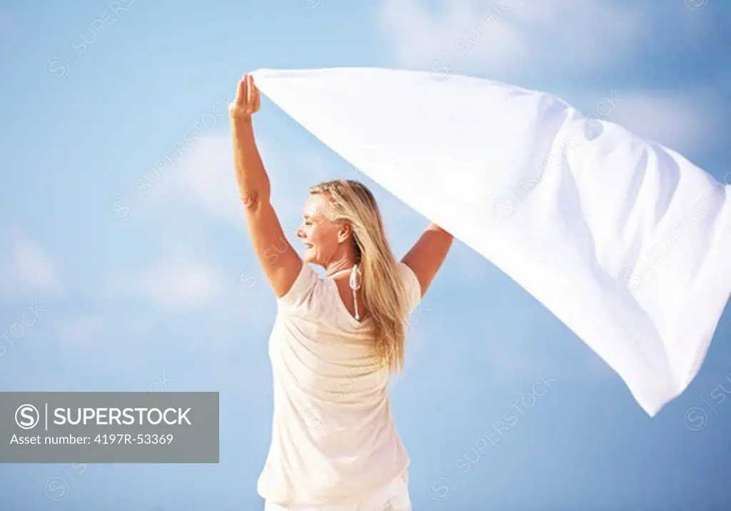 Portrait of mature woman with flying sarong against blue sky