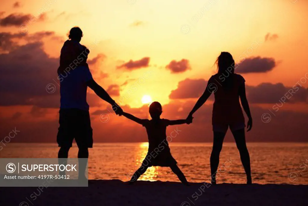 Silhouette of family enjoying the beautiful sunset on the beach