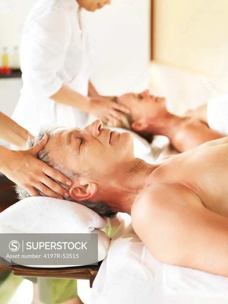 Image of mature man and woman having massage in spa salon