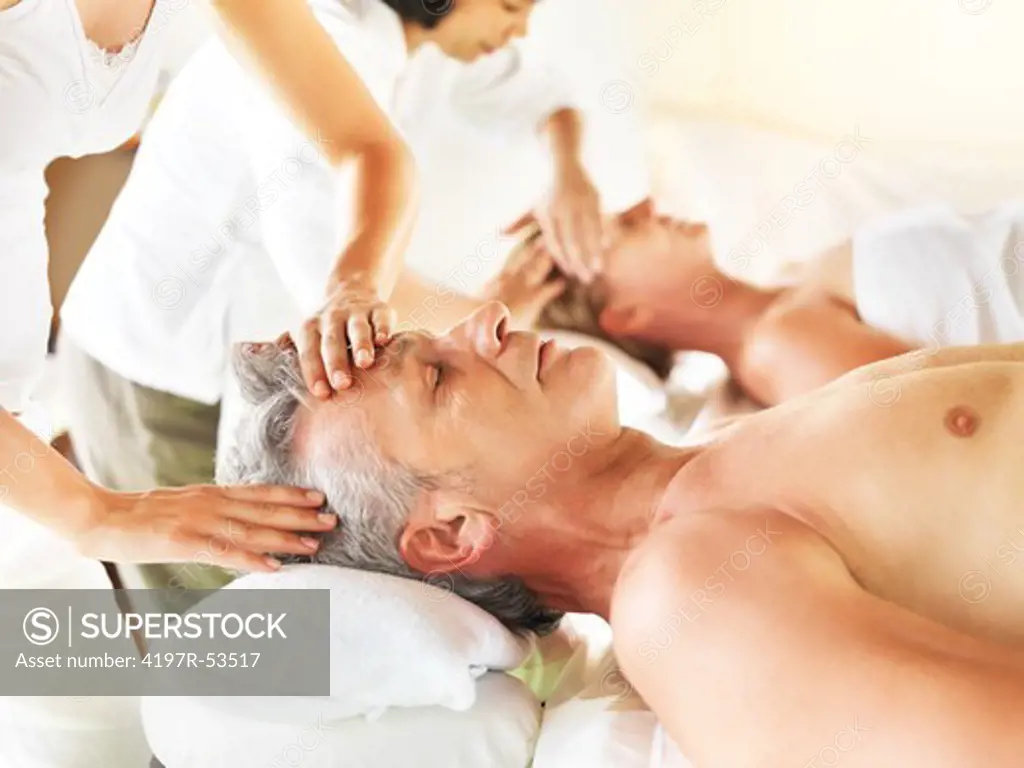 Relaxed mature couple receiving a massage in a spa center