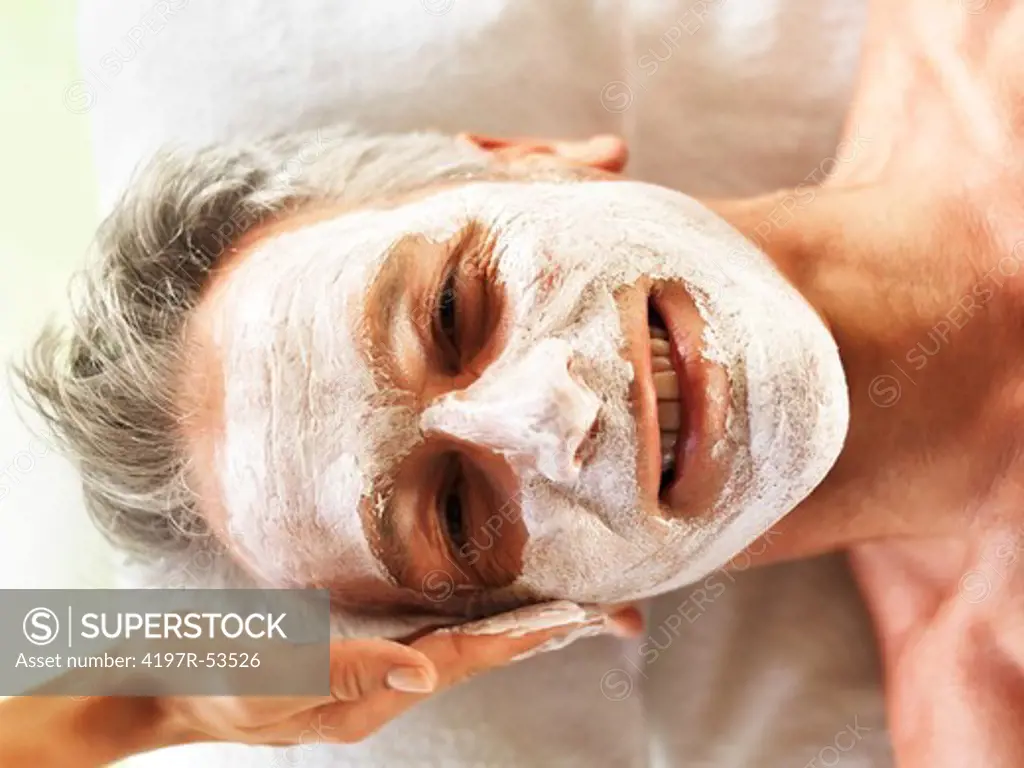 Closeup of happy mature man receivng spa facial treatment