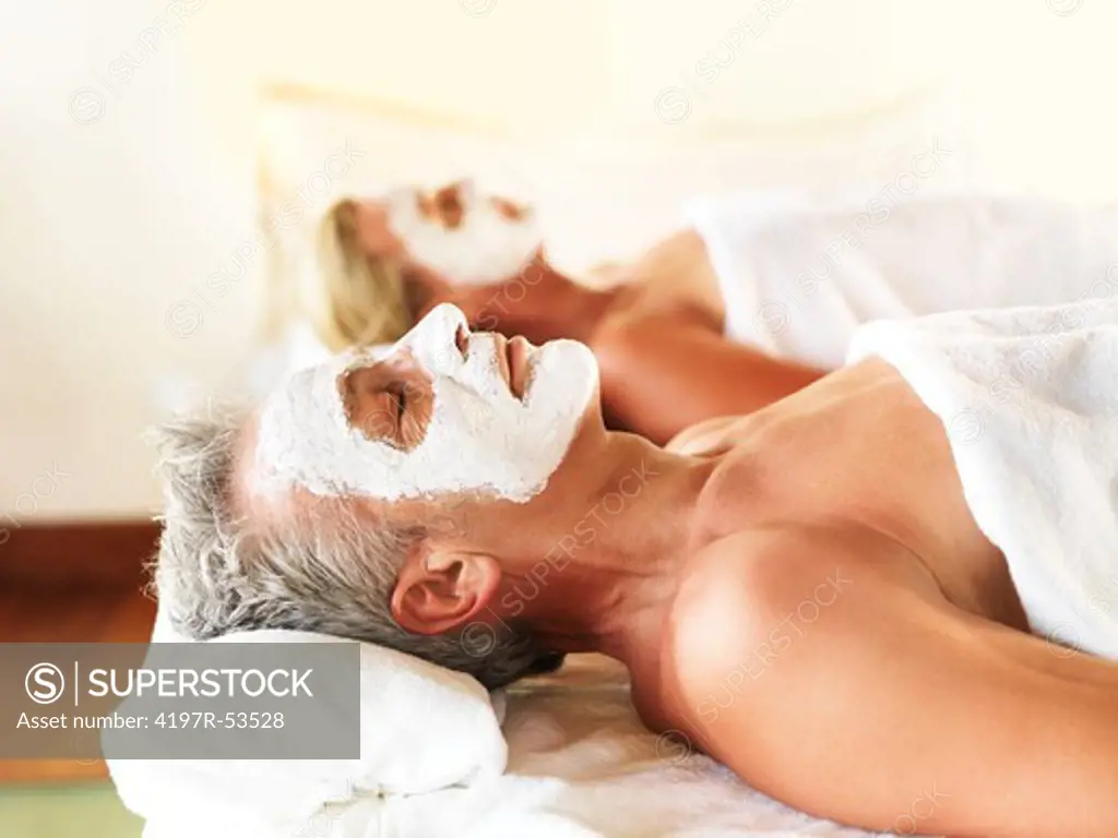 Mature couple having pore cleaning procedure on face at spa resort