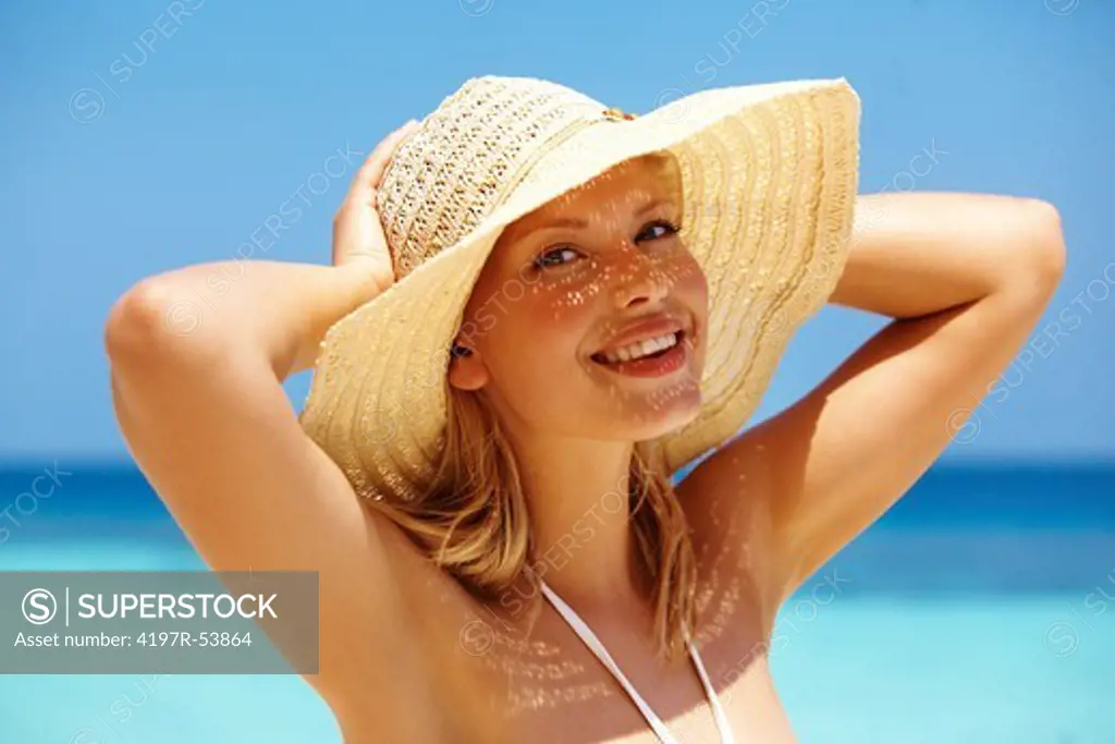 Beautiful young woman on the beach with a straw hat on
