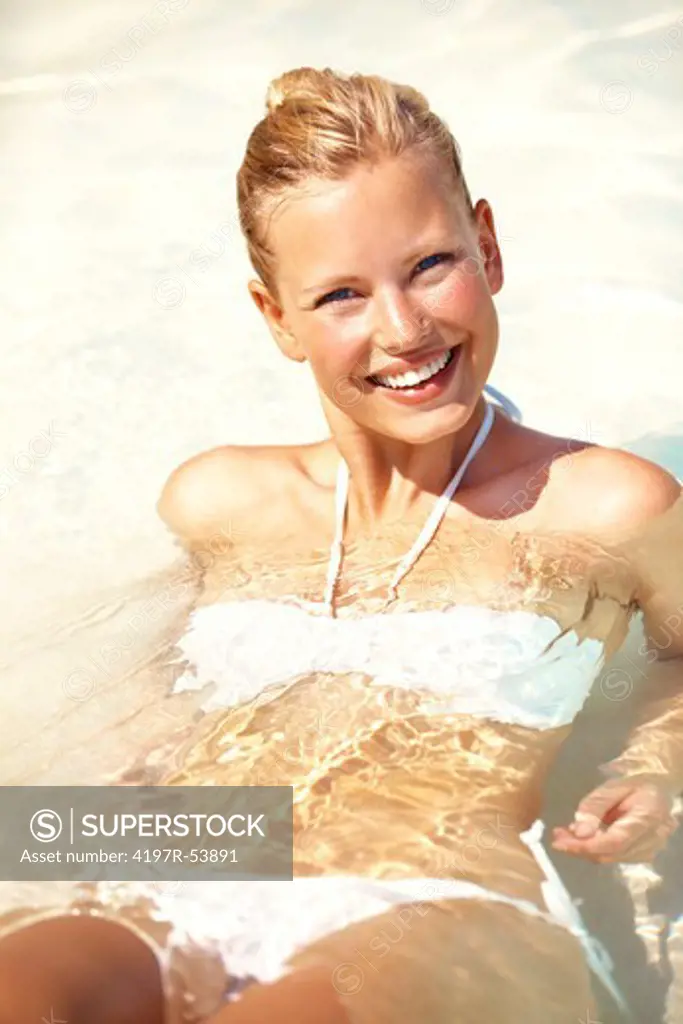 Happy and pretty young female lying in crystal clear ocean water
