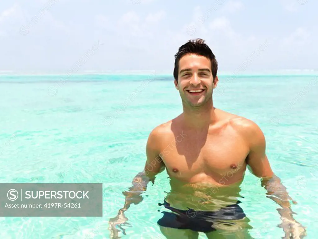Portrait of a smiling handsome man chest deep in a perfect blue ocean