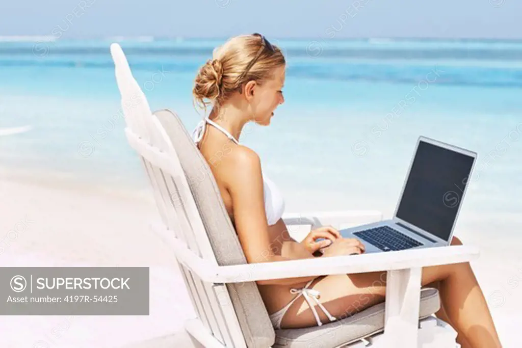 Portrait of young woman surfing internet while sitting on deck chair