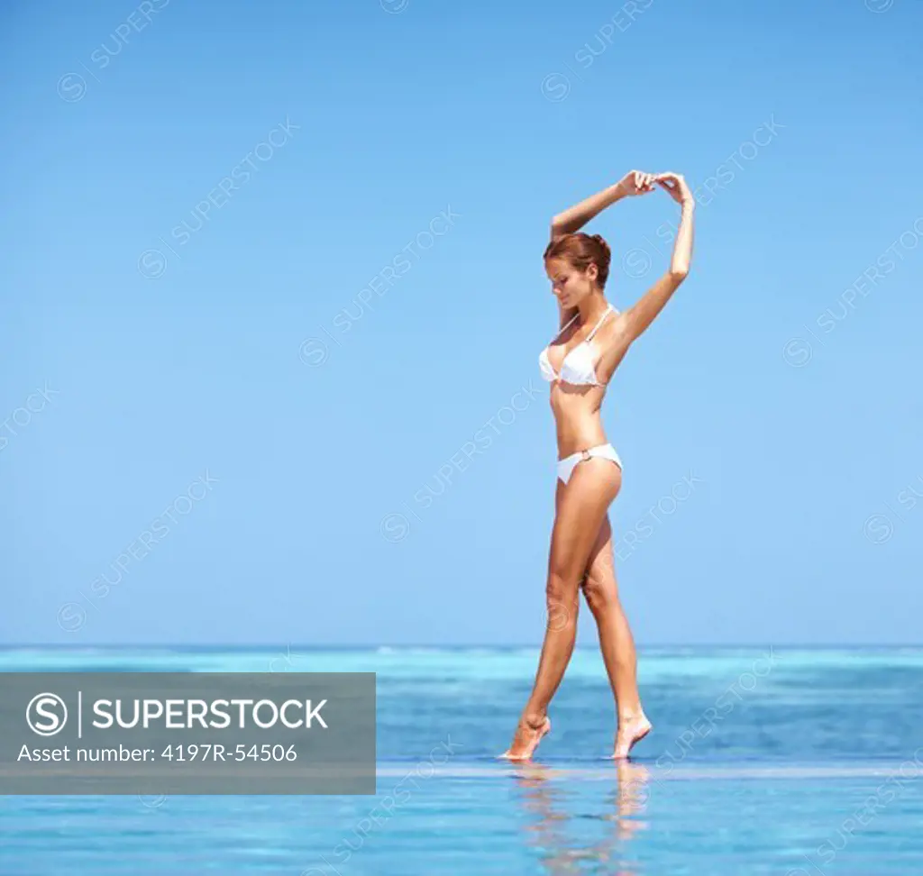 Pretty woman performing a ballet move by the pool