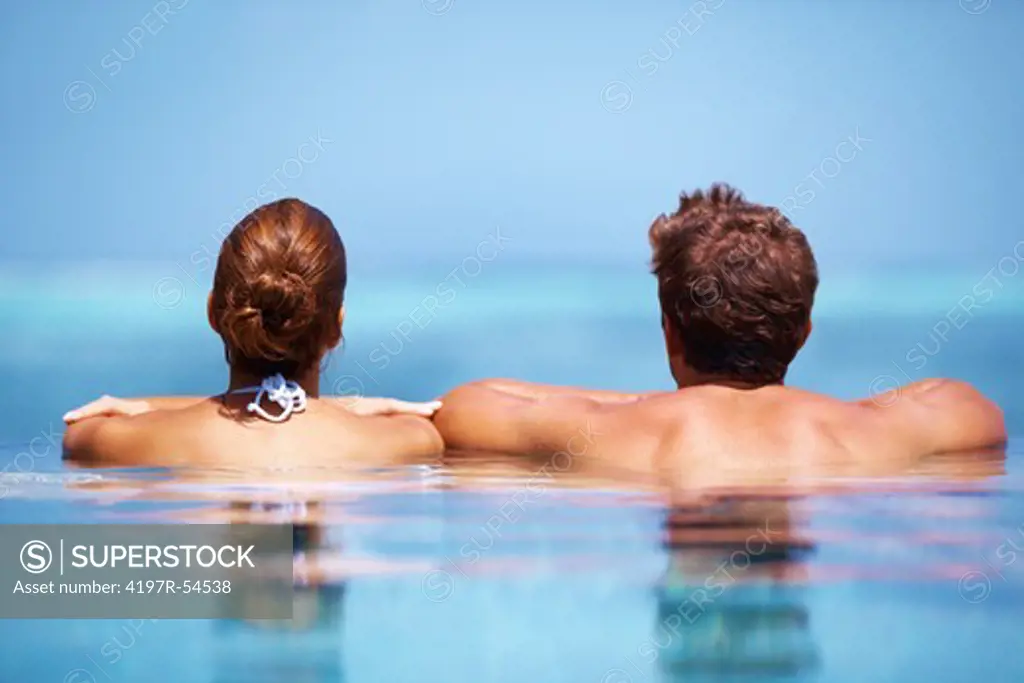Couple looking at the horizon from their pool