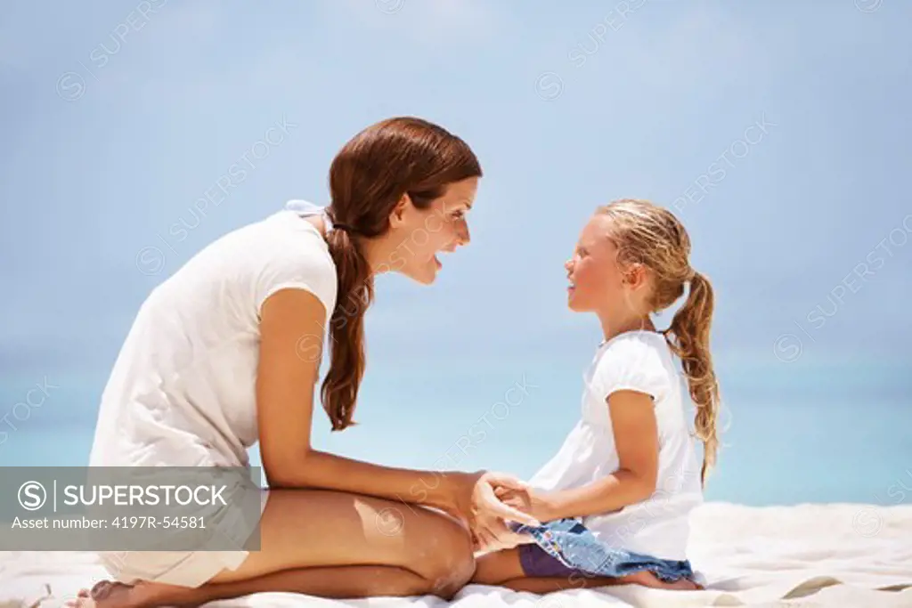 Attractive mother and daughter sitting on some towels outdoors