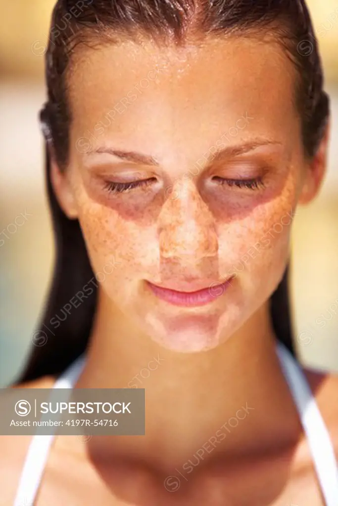 Young woman tanning her face with eyes closed