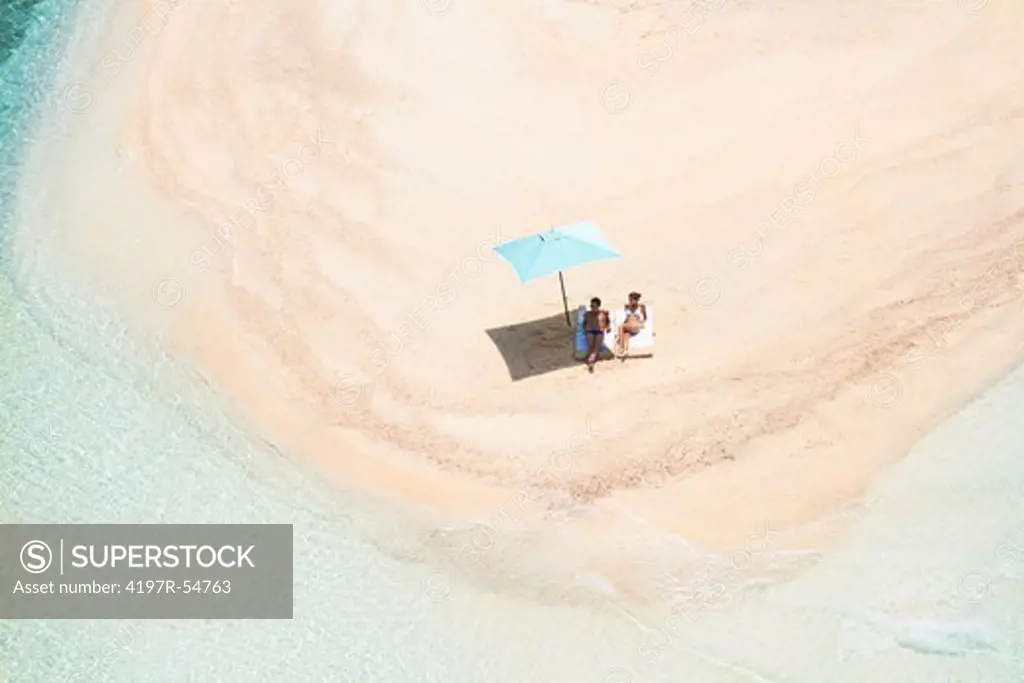 upper shot from jet of male and female sunbathing on paradise island