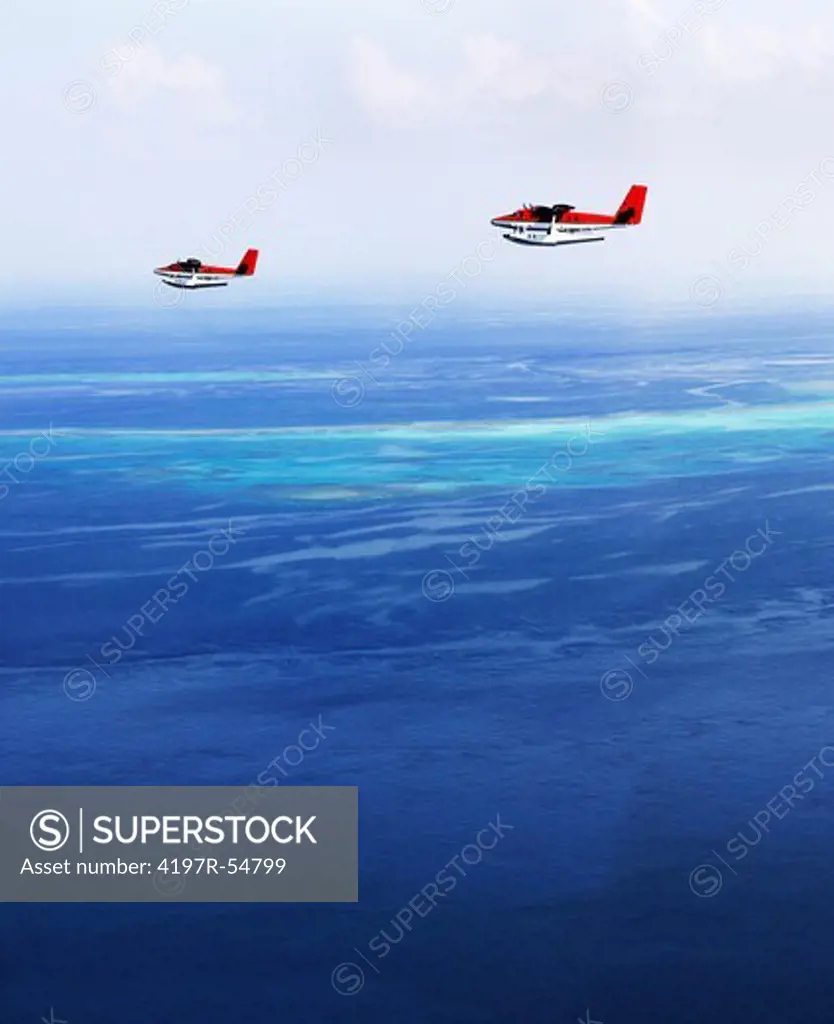Two smal floatplanes flying over the beautiful big blue ocean together