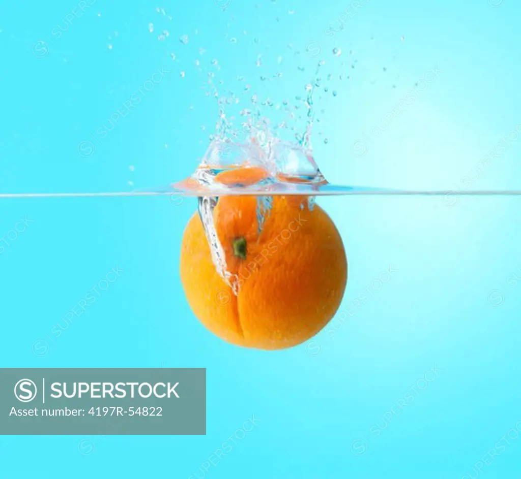 Juicy orange dropping into water and creating a little splash