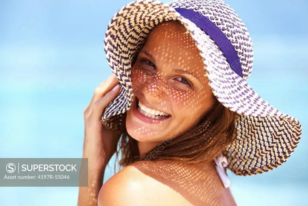 Closeup of cheerful young woman enjoying under summer hat