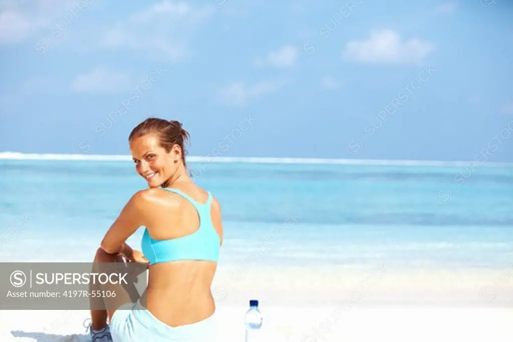 Portrait of charming young woman smiling while sitting at seashore