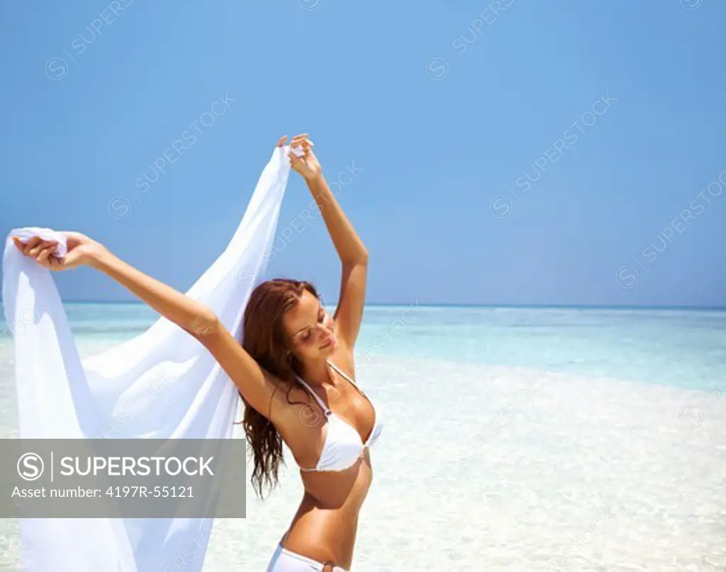 Portrait of peaceful woman holding sarong at beautiful beach