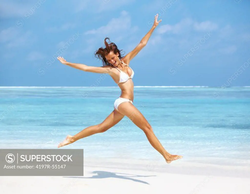 Portrait of carefree young woman jumping on the beach