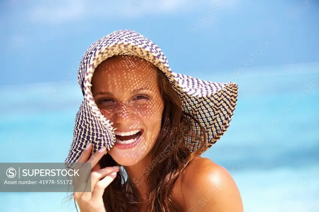 Closeup of carefree young woman enjoying while wearing sun hat