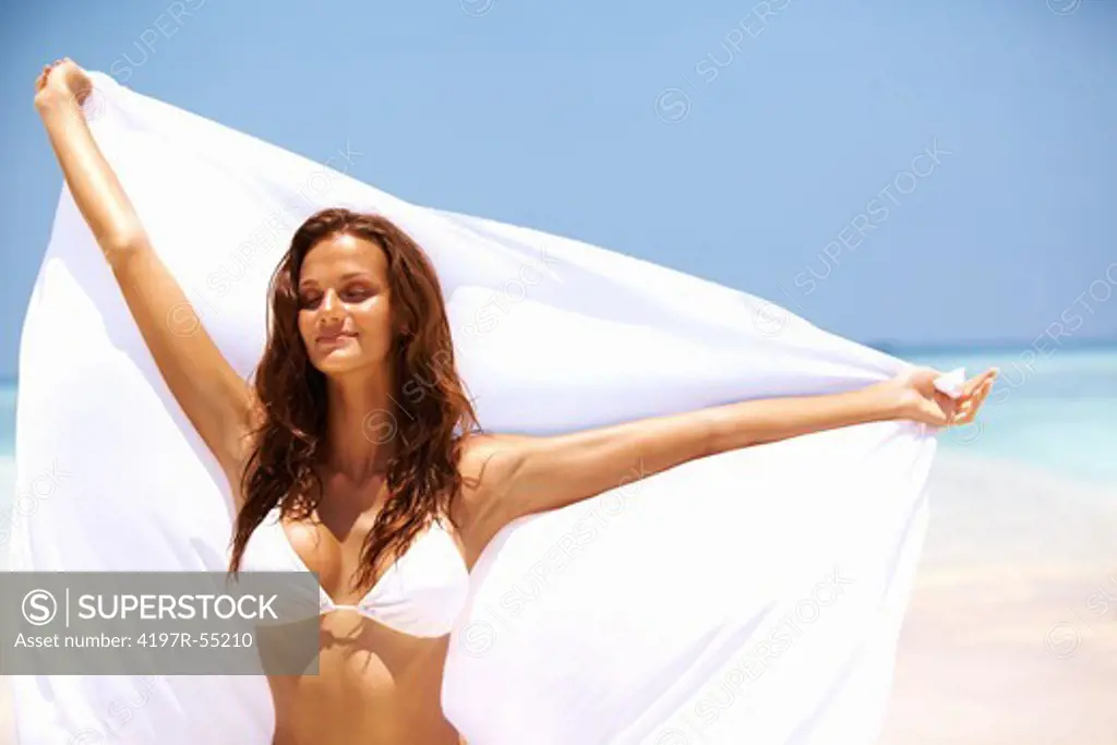 Portrait of calm young woman holding white sarong at beach