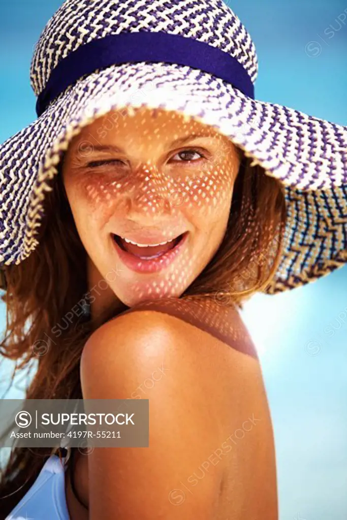 Closeup of flirtatious young woman winking in sun hat