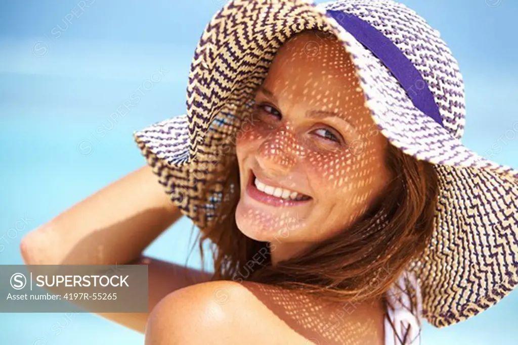 Closeup of young woman enjoying summer at beach wearing hat