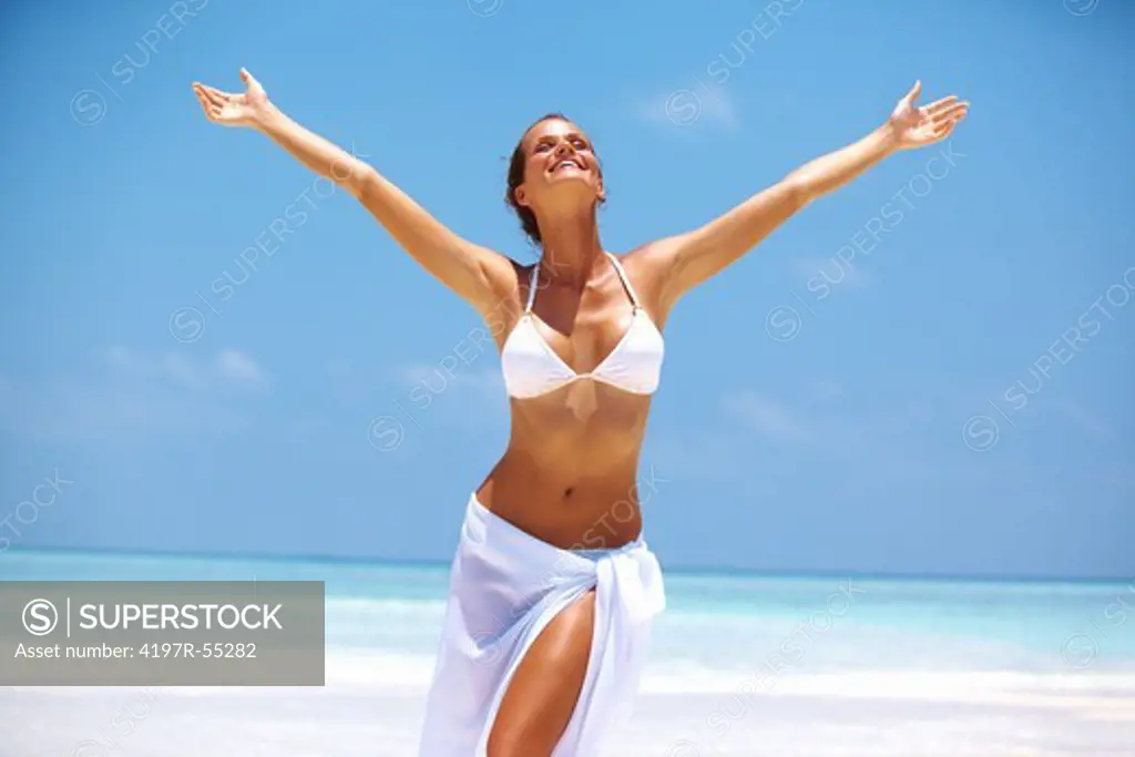 Portrait of carefree woman enjoying with arms outstretched at beach