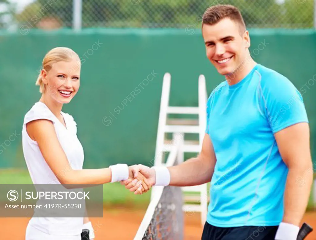 Smiling young tennis players shaking hands after a match