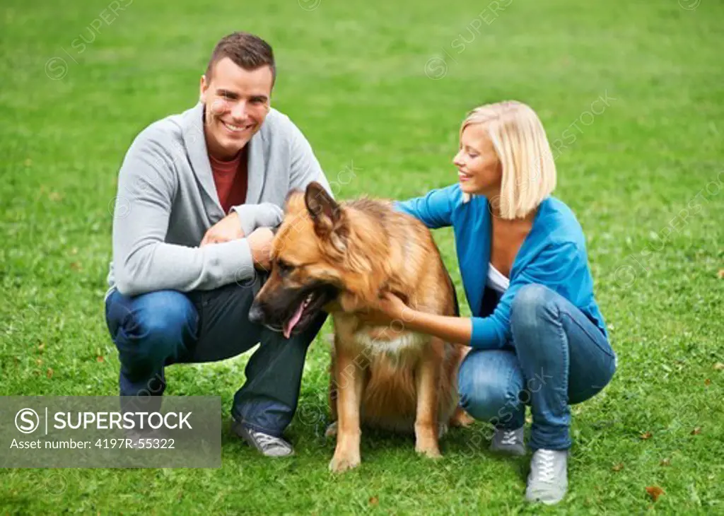 Happy young couple and their German Sheperd sitting in a park