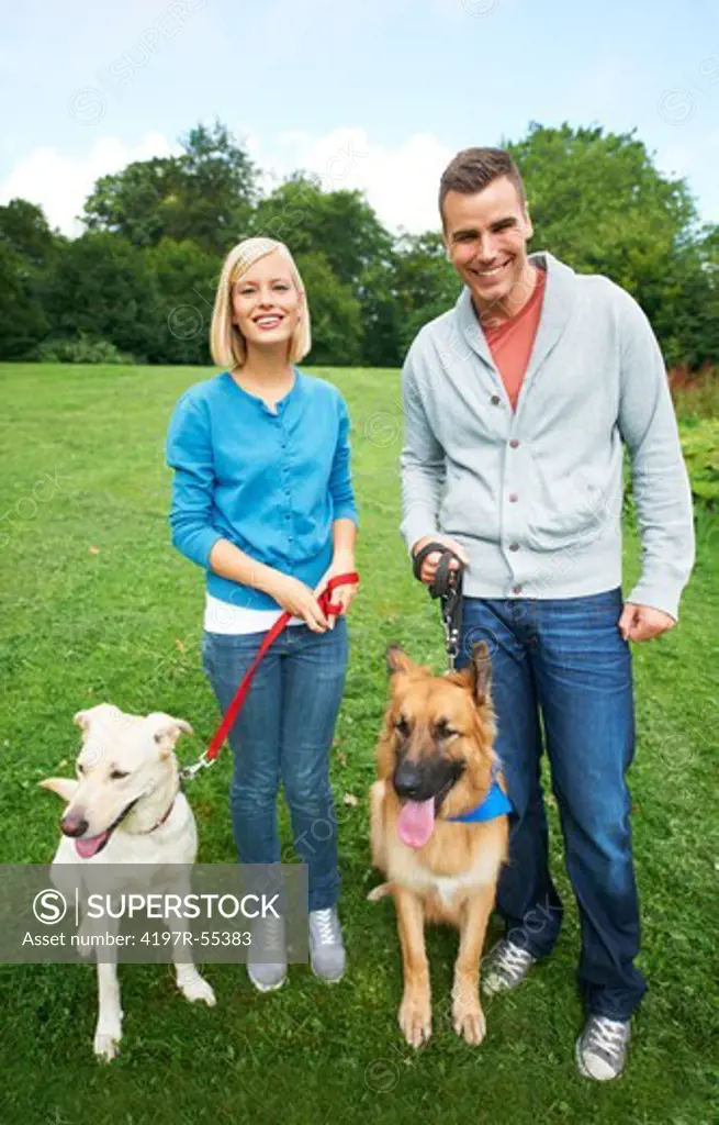 Happy young couple at the dog park with their dogs - portrait