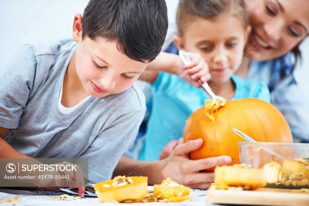 Children carving jack-o-lanterns for Halloween with their mother